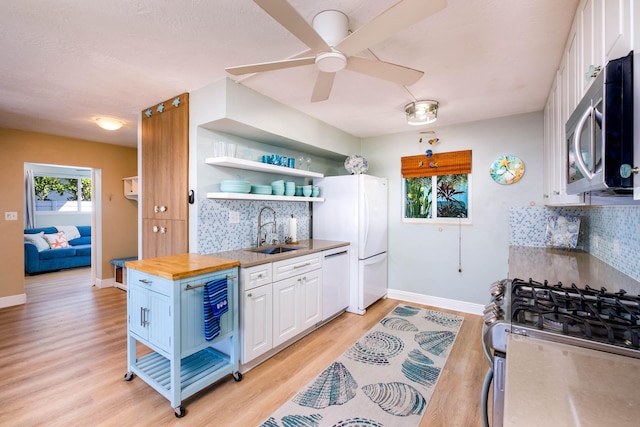 kitchen with sink, butcher block countertops, appliances with stainless steel finishes, white cabinetry, and light hardwood / wood-style floors