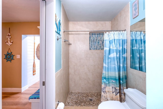 bathroom featuring toilet, curtained shower, and hardwood / wood-style floors