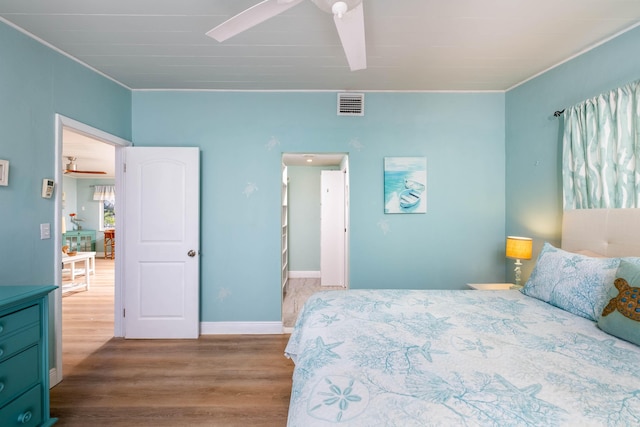 bedroom with hardwood / wood-style flooring, ornamental molding, and ceiling fan