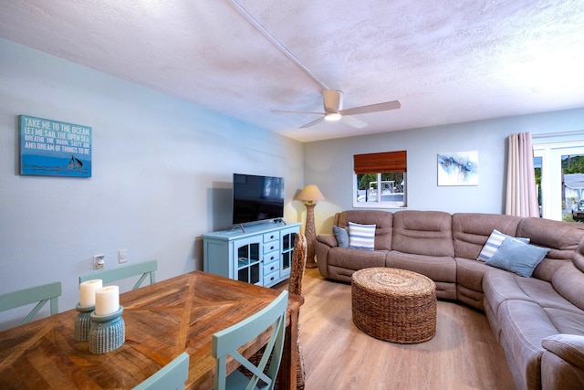 living room featuring a textured ceiling, light hardwood / wood-style flooring, and ceiling fan