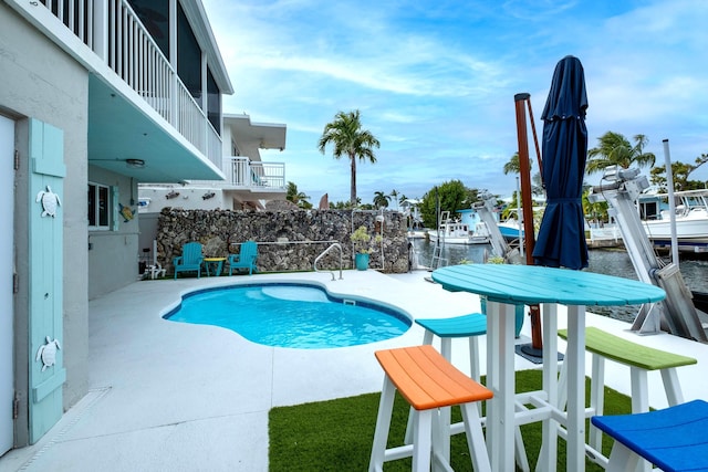 view of pool featuring a water view and a patio