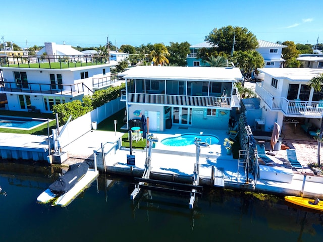 rear view of property featuring a water view, a community pool, a sunroom, and a patio area