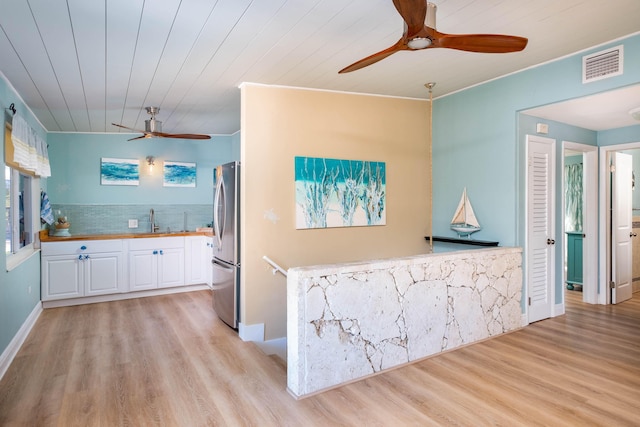 kitchen with butcher block countertops, white cabinetry, wooden ceiling, light wood-type flooring, and stainless steel fridge