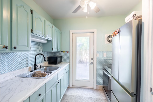 kitchen featuring appliances with stainless steel finishes, sink, backsplash, and ceiling fan