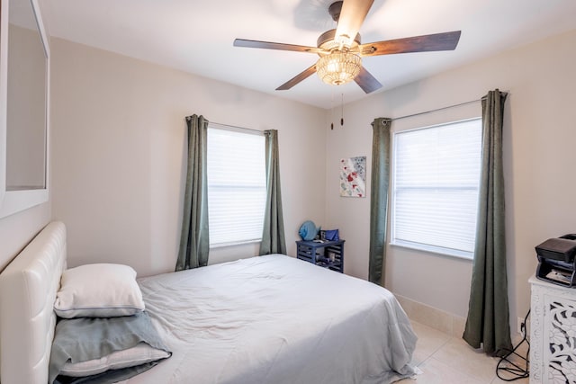 bedroom featuring ceiling fan, multiple windows, and light tile patterned floors