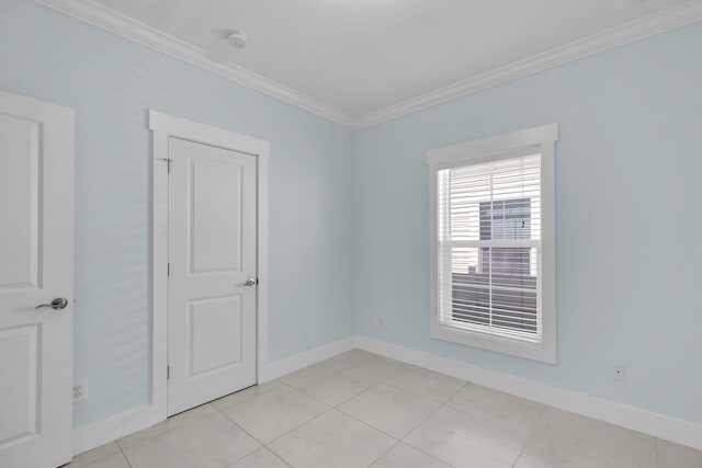 spare room with crown molding and light tile patterned floors