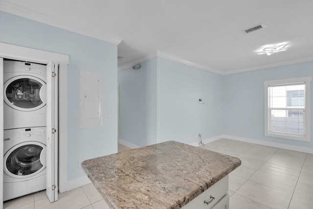 laundry room with stacked washer and dryer, ornamental molding, light tile patterned floors, and electric panel