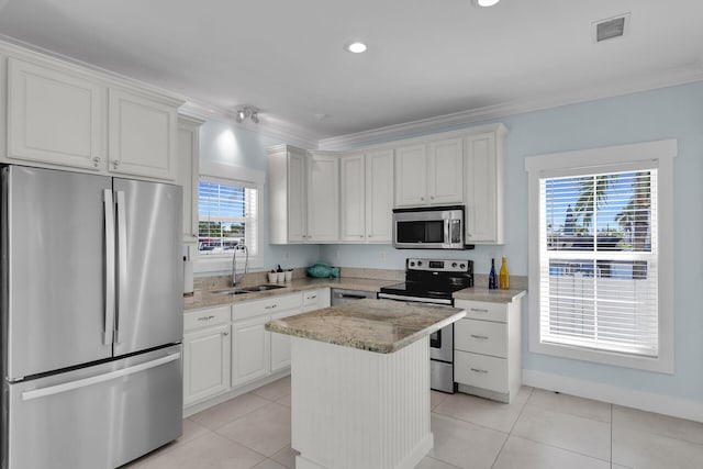 kitchen with sink, a center island, ornamental molding, appliances with stainless steel finishes, and white cabinets