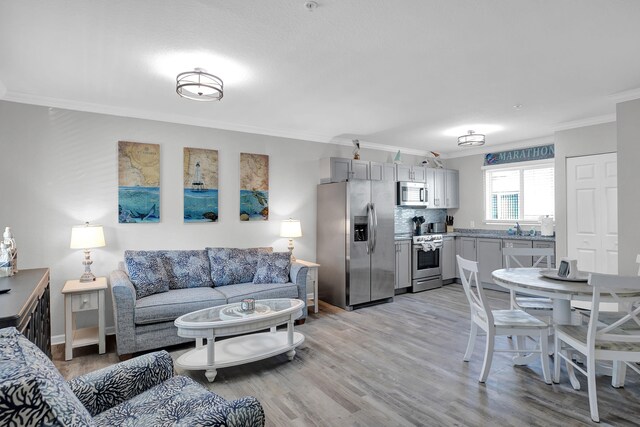 living room featuring sink, crown molding, and light hardwood / wood-style floors