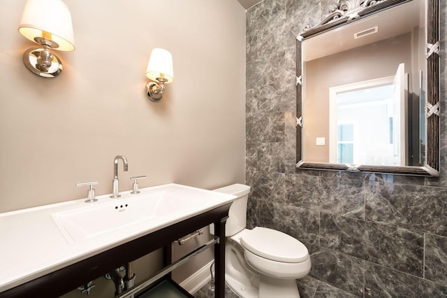 bathroom with sink, tile walls, and toilet