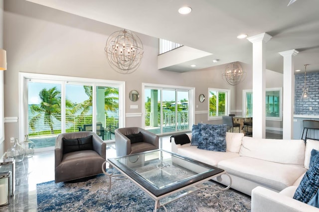 living room featuring a notable chandelier, vaulted ceiling, and ornate columns