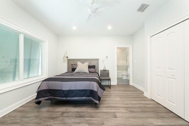 bedroom featuring hardwood / wood-style flooring, connected bathroom, and a closet