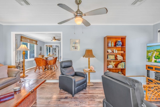 living room with crown molding, ceiling fan, and light hardwood / wood-style floors