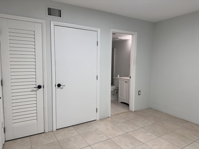 unfurnished bedroom featuring connected bathroom and light tile patterned floors