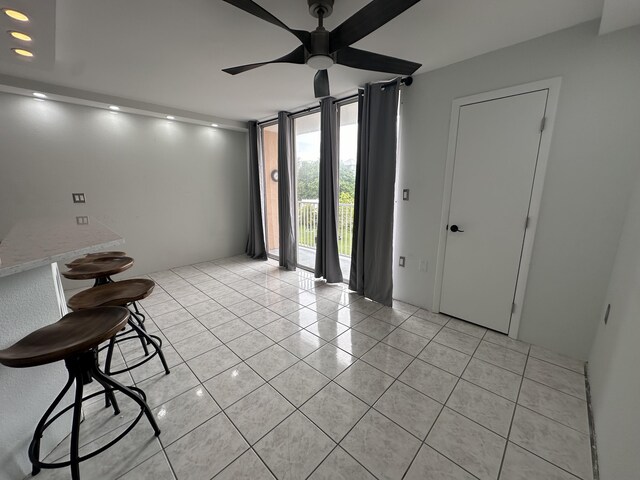 interior space with light tile patterned floors, expansive windows, and ceiling fan