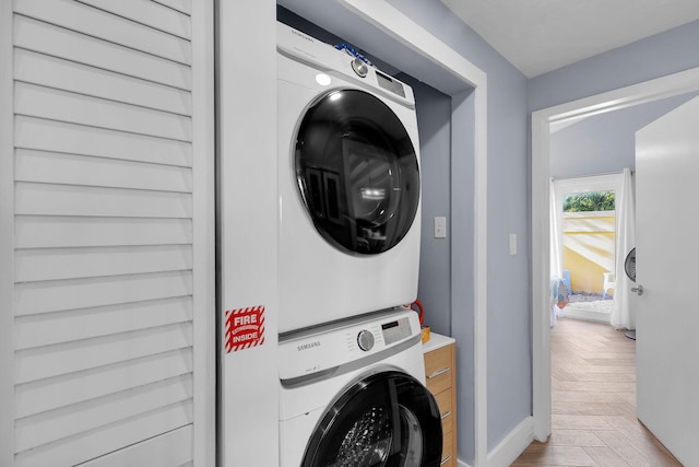 laundry room featuring light parquet flooring and stacked washer and clothes dryer