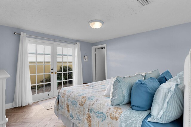 bedroom featuring french doors, a textured ceiling, and light parquet floors