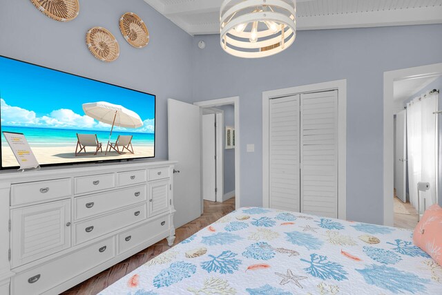 bedroom with light parquet floors, a notable chandelier, and a closet