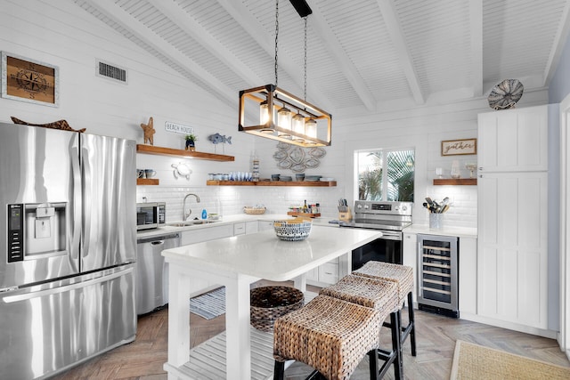 kitchen featuring sink, stainless steel appliances, decorative light fixtures, beverage cooler, and light parquet flooring