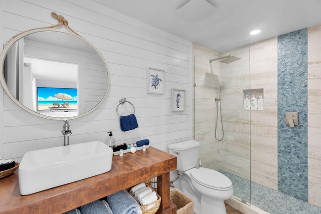 bathroom with a tile shower, sink, and toilet