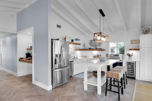 kitchen with a kitchen island, a breakfast bar, white cabinetry, beverage cooler, and stainless steel appliances