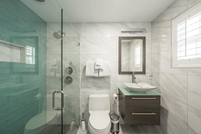 bathroom with vanity, toilet, an enclosed shower, and tile walls