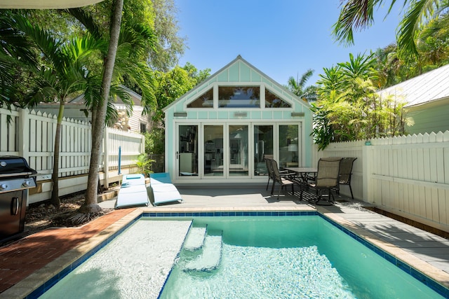 rear view of property featuring an outbuilding and a fenced in pool