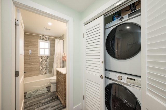 laundry room with stacked washing maching and dryer and dark hardwood / wood-style flooring