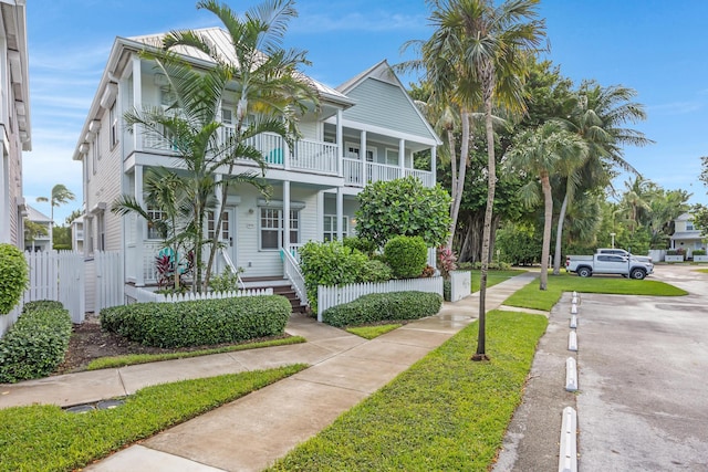 view of front of house with a porch, a balcony, and fence