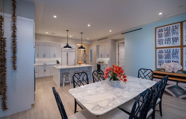 dining area featuring beverage cooler and light hardwood / wood-style floors