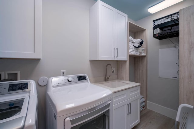 washroom with sink, hardwood / wood-style floors, cabinets, and washing machine and clothes dryer