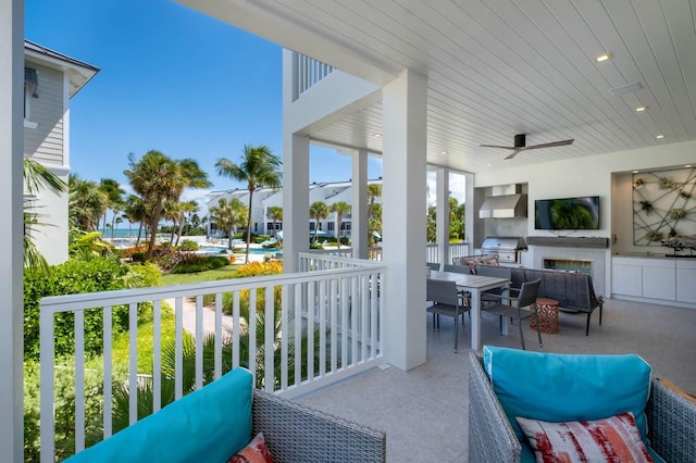 balcony featuring a patio area, area for grilling, ceiling fan, an outdoor living space, and exterior kitchen