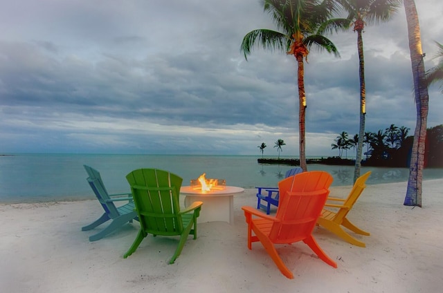 view of patio / terrace featuring a view of the beach, a water view, and an outdoor fire pit