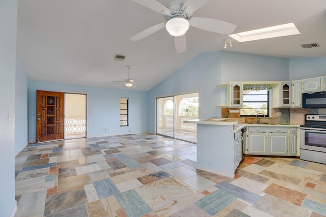 kitchen featuring sink, a skylight, stainless steel appliances, tasteful backsplash, and kitchen peninsula