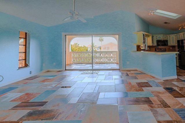 unfurnished living room featuring vaulted ceiling with skylight and ceiling fan