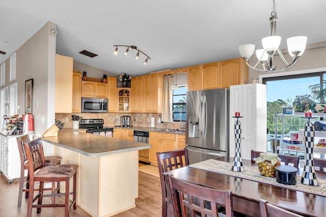 kitchen with pendant lighting, backsplash, stainless steel appliances, a kitchen bar, and kitchen peninsula