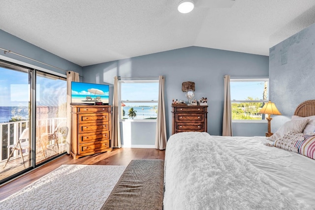 bedroom featuring hardwood / wood-style floors, vaulted ceiling, and a textured ceiling