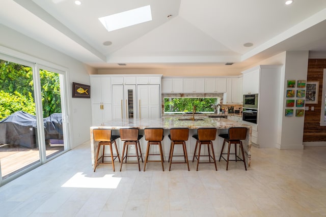 316 Southard St, Key West, FL 33040 - kitchen featuring white cabinets, a skylight, a sink, a spacious island, and light stone countertops
