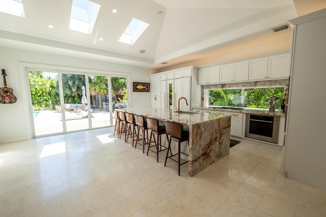 316 Southard St, Key West, FL 33040 - kitchen featuring oven, a sink, light stone counters, a skylight, and a breakfast bar area