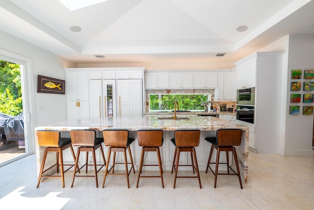 316 Southard St, Key West, FL 33040 - kitchen featuring a raised ceiling, white cabinets, a large island with sink, backsplash, and lofted ceiling