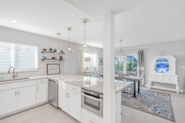 kitchen with pendant lighting, sink, white cabinetry, and kitchen peninsula