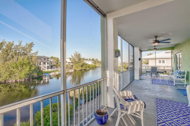 unfurnished sunroom featuring ceiling fan and a water view