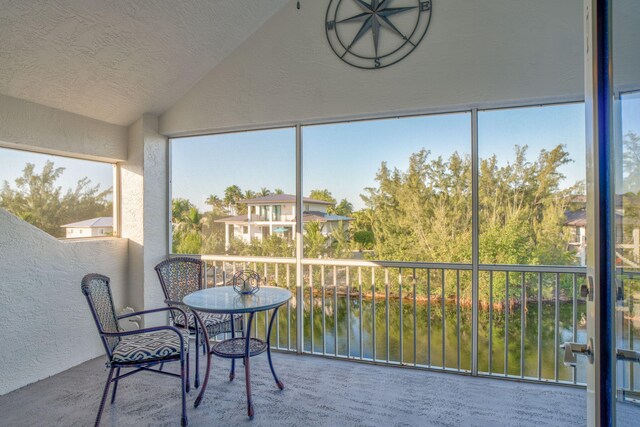 sunroom featuring vaulted ceiling and a water view