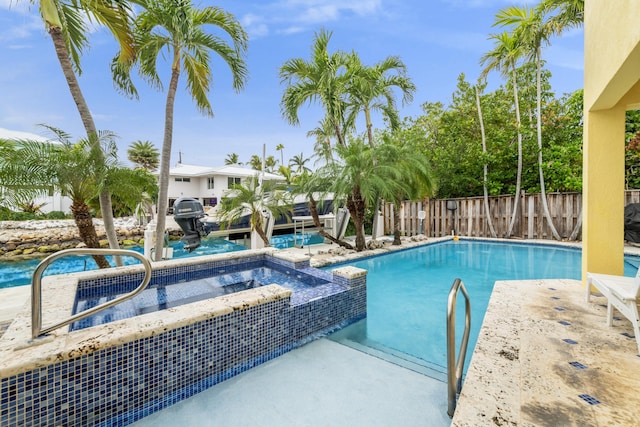 view of pool featuring a pool with connected hot tub, a dock, and fence