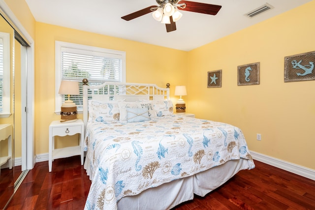 bedroom with dark wood-type flooring, ceiling fan, and a closet