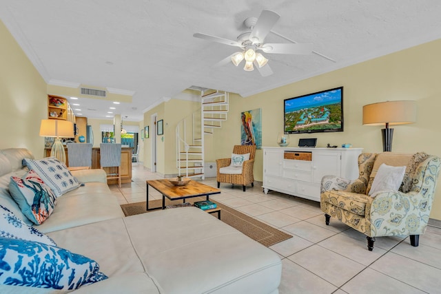 tiled living room featuring ceiling fan, ornamental molding, and a textured ceiling