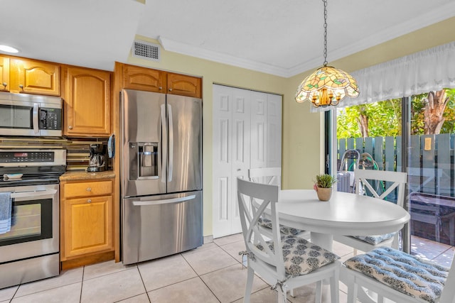 kitchen with ornamental molding, stainless steel appliances, hanging light fixtures, and light tile patterned floors