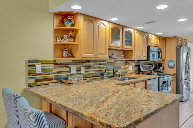 kitchen featuring light stone countertops, stainless steel appliances, and kitchen peninsula