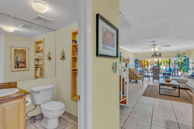 bathroom featuring tile patterned flooring, vanity, ceiling fan, toilet, and a textured ceiling