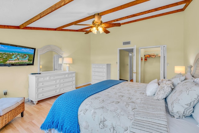 bedroom with lofted ceiling with beams, a spacious closet, ceiling fan, and light hardwood / wood-style flooring